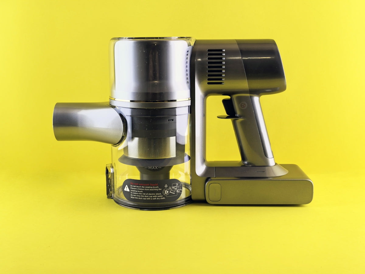 A modern cordless vacuum against a yellow backdrop.