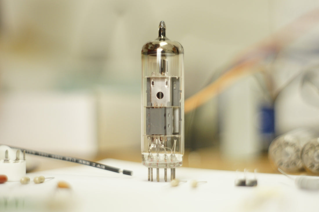 A single vacuum tube sits on a workbench.